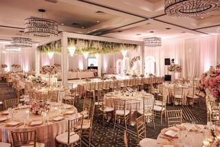 A beautifully decorated banquet hall featuring elegant tables, floral arrangements, and chandeliers, all exuding a romantic ambiance.