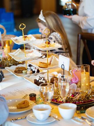 A beautifully set table featuring tiered stands with assorted treats, elegant dishes, and a child enjoying the delightful spread.