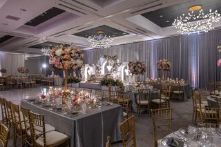 An elegantly decorated banquet hall featuring floral centerpieces, gold accents, and soft lighting, perfect for a luxurious celebration.