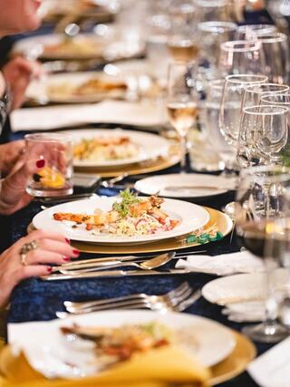 A beautifully set dining table features elegant plates of gourmet food, sparkling glasses, and an inviting atmosphere for a lavish meal.