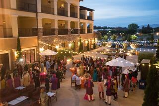 A vibrant outdoor gathering with guests in colorful attire, enjoying an evening adorned with string lights and festive decorations.