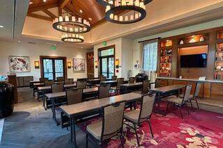 A stylish conference room featuring wooden beams, multiple tables, chairs, and a cozy ambiance with decorative lighting and artwork.