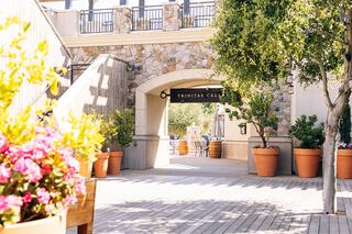 A charming stone archway leads to a vibrant courtyard, adorned with potted flowers and greenery, inviting visitors to explore.