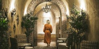 A serene pool area lined with lounge chairs, umbrellas, and lush greenery, offering a tranquil retreat against a backdrop of hills.