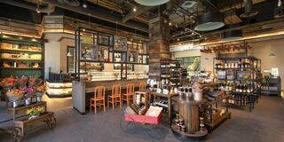 A cozy, modern marketplace features wooden decor, a variety of products, and seating, creating an inviting atmosphere.