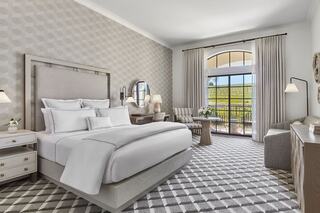 A stylish, modern luxury hotel room features a queen bed, elegant decor, and large windows with views, creating a tranquil and inviting atmosphere.