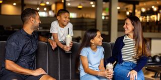 A smiling family enjoys ice cream together in a cozy, modern setting, sharing laughter and joyful moments.