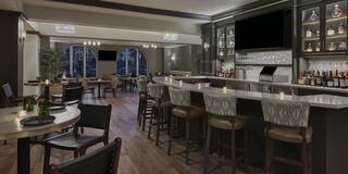 A stylish bar area featuring elegant seating, a well-stocked liquor display, and ambient lighting, creating a sophisticated atmosphere.