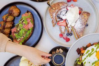 A variety of delicious dishes, including French toast topped with berries and ice cream, alongside savory items and dipping sauces.