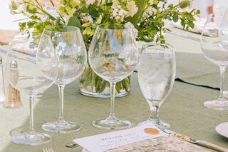 A beautifully arranged dining table features elegant glassware, a water glass, and a bouquet of flowers, creating a sophisticated ambiance.