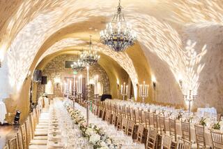 A stunning banquet hall with elegant chandeliers, long tables adorned with flowers, and a warm, inviting atmosphere. Perfect for celebrations.