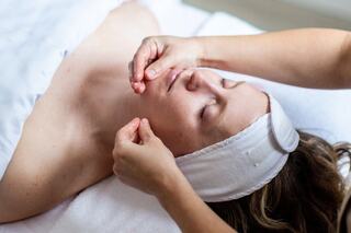 A couple stands happily together, dressed elegantly for their wedding, surrounded by floral arrangements and a beautifully lit cake.