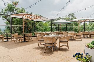 A cozy outdoor dining space featuring stylish wooden furniture, large umbrellas, and vibrant greenery, providing a relaxed atmosphere for guests.