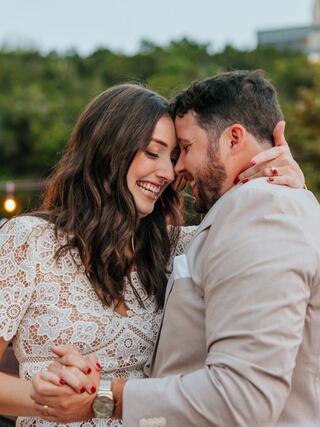 A joyful couple shares a close, intimate moment, smiling and dancing together, surrounded by a scenic outdoor backdrop.