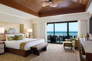 A luxurious hotel room with modern decor, featuring a king-sized bed, stylish furniture, and a stunning ocean view through large windows.