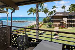 A serene balcony view showcases palm trees, a sandy beach, and turquoise waters, creating a tropical paradise atmosphere.