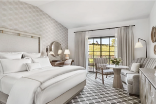 A stylish, modern luxury bedroom featuring a plush bed, elegant decor, cozy seating area, and large windows with natural light.