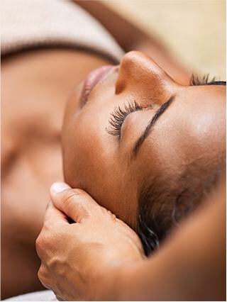 A woman lies relaxed with her eyes closed, while a hand gently cradles her head, conveying a sense of calm and serenity.
