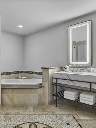 A modern bathroom features a corner tub, double sink vanity with sleek fixtures, and decorative tile flooring for a stylish look.
