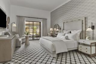 A stylish, modern luxury hotel room features a plush bed, comfortable seating, and large windows overlooking a serene outdoor space.