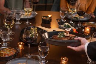 A beautifully set dining table featuring gourmet dishes, elegant glassware, and warm candlelight, creating an inviting atmosphere for gathering.