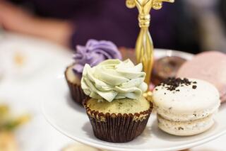 A tiered stand showcases colorful cupcakes with swirled frosting and delicate macarons, creating a tempting dessert display.
