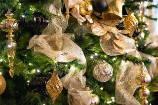 A festive display of gold and black ornaments, sparkling ribbons, and twinkling lights adorn a beautifully decorated Christmas tree.
