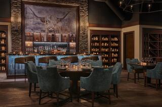 A cozy restaurant interior featuring plush blue chairs, a well-stocked bar, and rustic decor, highlighted by a striking animal portrait.