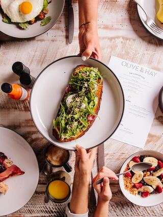 A delicious brunch scene featuring a colorful salad on toast, coffee, juices, and a vibrant menu highlighted on a rustic wooden table.