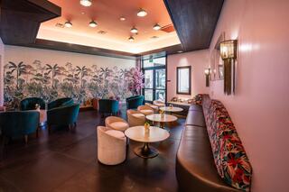 A chic lounge features plush seating, vibrant decor, and a tropical mural, creating a stylish and inviting atmosphere for relaxation.