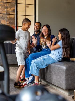 A happy family shares laughter and joy while sitting on a couch, enjoying each other’s company in a cozy, modern space.