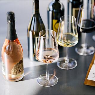 A stylish display of wine bottles and glasses, featuring a mix of rosé, white, and red wines, set against a sleek surface.