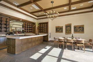 A stylish restaurant interior features a spacious bar with wine storage, elegant chandeliers, wooden accents, and a cozy dining area.