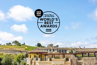 A picturesque landscape features vineyards and elegant buildings under a clear sky, promoting the Travel + Leisure World's Best Awards 2026.