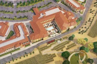 Aerial view of a resort complex featuring multiple buildings, landscaped areas, and vineyards, showcasing architectural design and greenery.