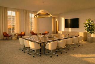 A modern conference room featuring a long table, comfortable chairs, large windows with natural light, and stylish decor.