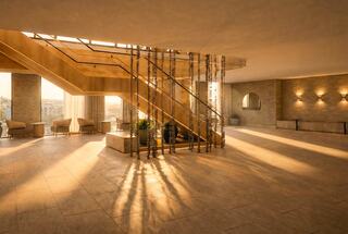 A spacious, modern foyer features a stylish staircase, warm lighting, and soft shadows, creating a welcoming atmosphere.