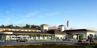 A stylish building with a Mediterranean-inspired design, featuring columns, arches, and a vibrant landscape, set against a clear blue sky.