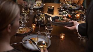 A group dining experience showcases elegant dishes, fine wines, and warm candlelight, creating a sophisticated atmosphere for sharing.