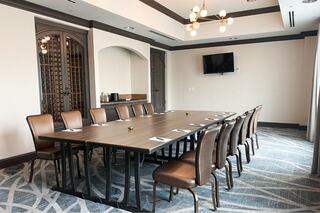 A spacious meeting room featuring a long table adorned with potted succulents, an elegant ambiance, and tasteful artwork on the walls.