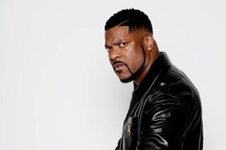 A man in a stylish black leather jacket exudes confidence, showcasing a fierce expression and a well-groomed hairstyle.